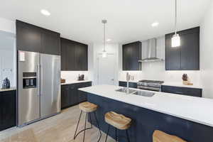 Kitchen with high end appliances, hanging light fixtures, a breakfast bar, light wood finished floors, and light stone counters