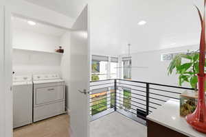 Laundry area with light colored carpet, recessed lighting, washer and dryer, and light tile patterned floors