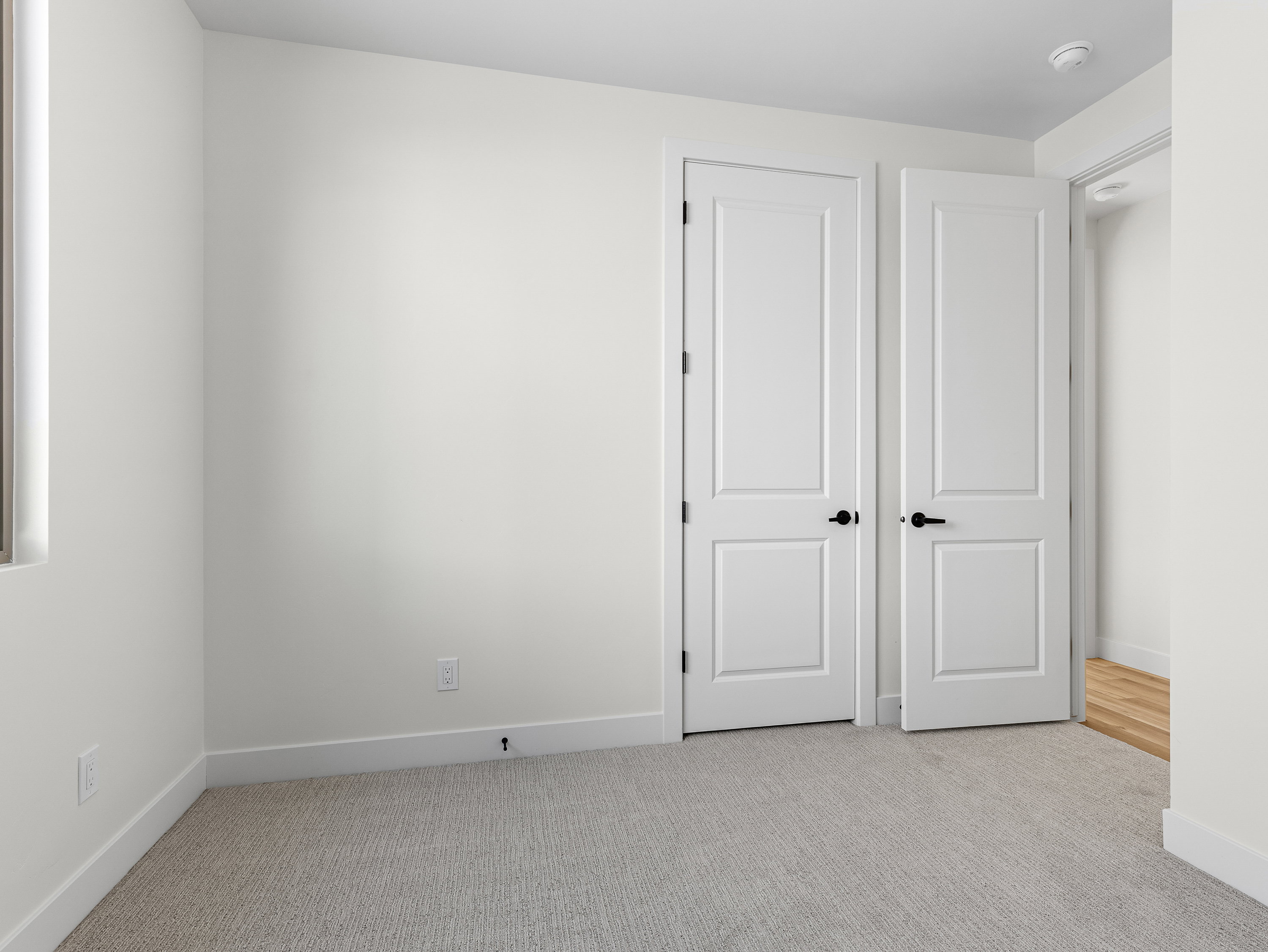Unfurnished bedroom with light carpet and baseboards