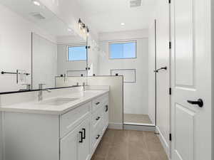 Full bathroom with double vanity, a marble finish shower, recessed lighting, and light tile patterned floors