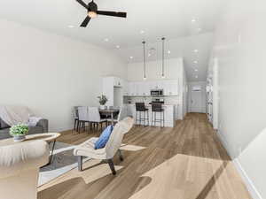 Living room featuring light wood finished floors, a ceiling fan, recessed lighting, and vaulted ceiling