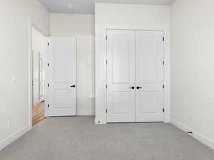 Unfurnished bedroom with light carpet and a closet