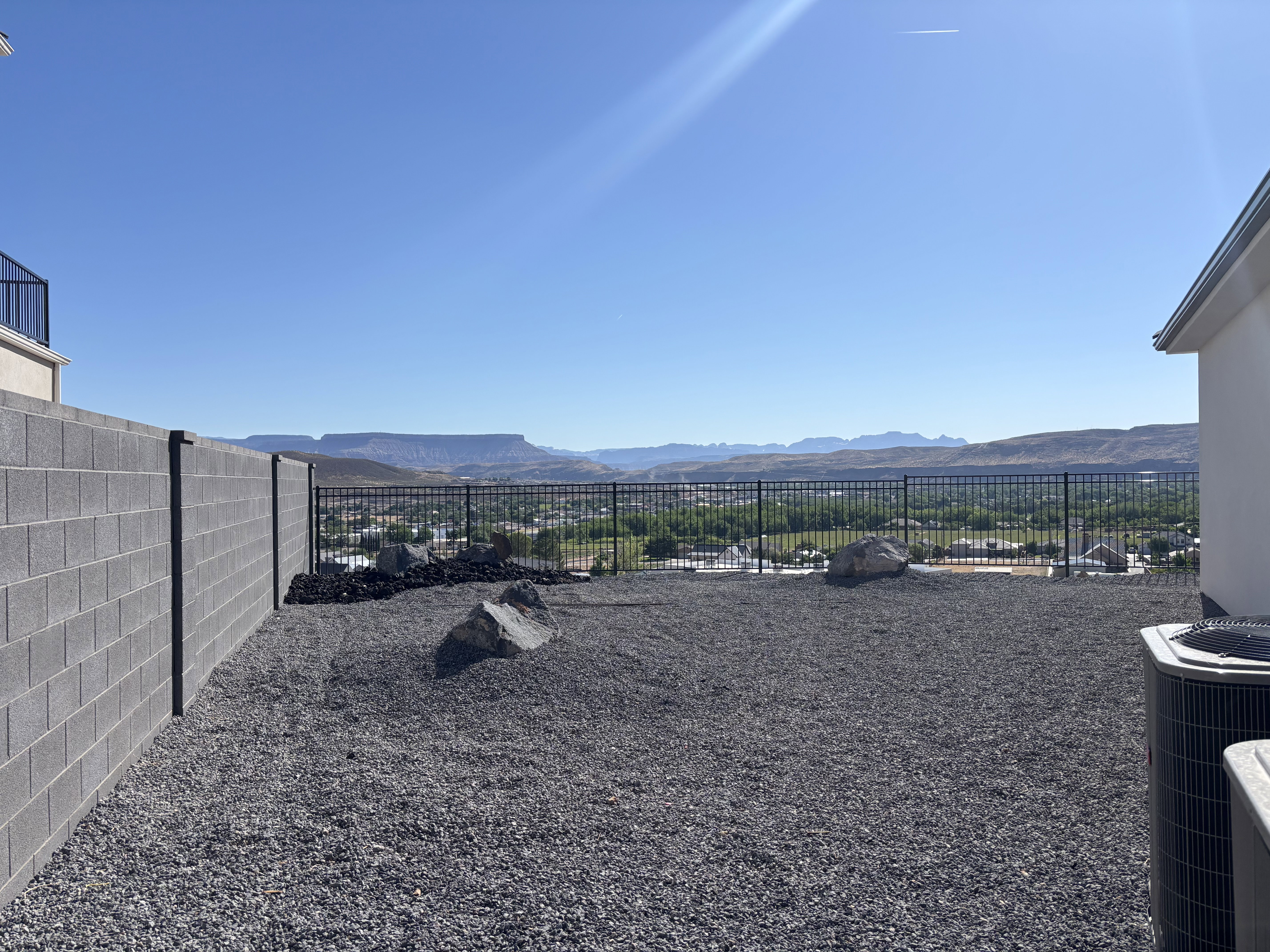 Expansive outdoor space featuring a gravel ground cover and a low-maintenance block wall