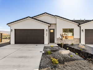 View of front of home with an attached garage, driveway, stone siding, stucco siding, and a tile roof