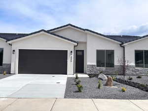 View of front of house with stone siding, a garage, concrete driveway, stucco siding, and a tiled roof