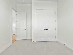 Unfurnished bedroom featuring light carpet and a closet