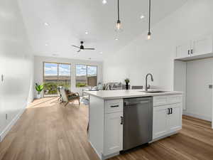 Kitchen featuring open floor plan, white cabinets, dishwasher, and light wood-type flooring