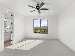Unfurnished bedroom with light carpet, a ceiling fan, a mountain view, recessed lighting, and connected bathroom