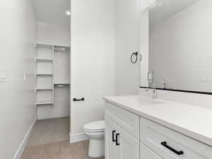 Bathroom featuring vanity, light tile patterned flooring, and a walk in closet