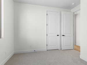 Unfurnished bedroom with light carpet and baseboards