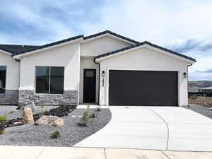 View of front of property with a garage, concrete driveway, stucco siding, and stone siding