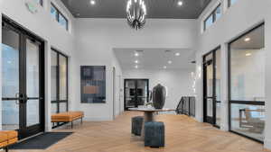 Entrance foyer with french doors, a high ceiling, parquet floors, and a chandelier