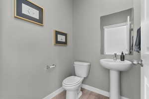 Half bathroom featuring toilet and light wood finished floors