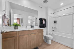 Full bathroom with vanity, washtub / shower combination, light wood finished floors, and recessed lighting