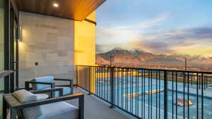 Balcony at dusk featuring a mountain view and view of pool