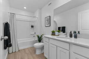 Full bath with vanity, light wood finished floors, and shower / bath combo