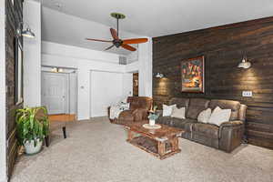Living area featuring lofted ceiling, carpet flooring, and a ceiling fan