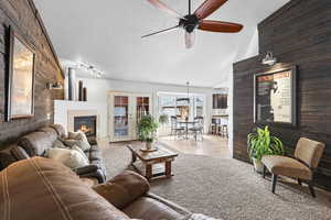 Living room featuring a fireplace, an accent wall, french doors, and ceiling fan
