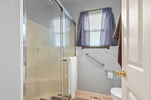 Bathroom with a shower stall and light tile patterned flooring