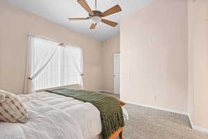 Bedroom featuring light colored carpet, a ceiling fan, and vaulted ceiling