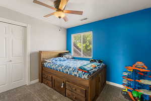 Carpeted bedroom featuring a ceiling fan and a closet