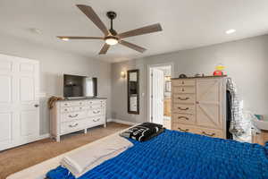 Primary bedroom featuring a ceiling fan, light colored carpet, and ensuite bathroom