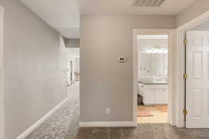 Hallway featuring light carpet and baseboards