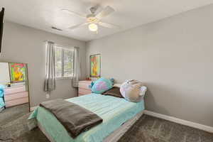 Bedroom with dark colored carpet and a ceiling fan