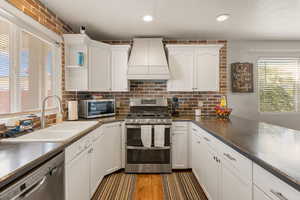 Kitchen with stainless steel appliances, white cabinetry, dark countertops, recessed lighting, and dark wood-style flooring
