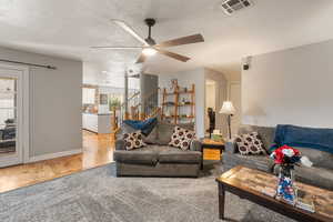 Living room featuring ceiling fan, wood finished floors, and a textured ceiling