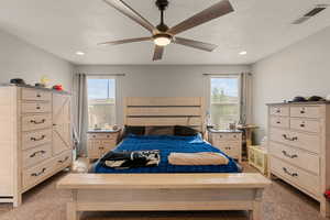 Primary bedroom with light carpet, a ceiling fan, recessed lighting, and a textured ceiling