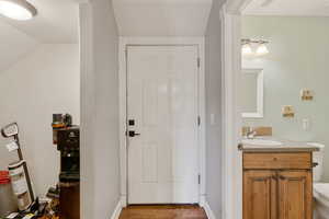 Half bathroom featuring vanity, wood finished floors, and lofted ceiling