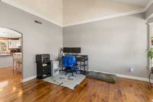 Family room featuring ornamental molding, vaulted ceiling, hardwood / wood-style floors, and arched walkways