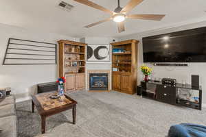 Carpeted living room featuring a fireplace, a ceiling fan, and a textured ceiling