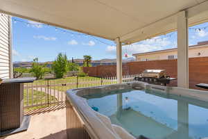 Fenced backyard featuring a hot tub, a patio, and a grill