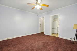 Unfurnished bedroom featuring crown molding, freestanding refrigerator, ceiling fan, and light colored carpet
