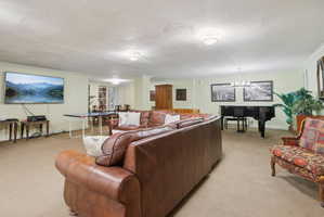 Living room featuring light colored carpet, crown molding, hanging lights, and a textured ceiling