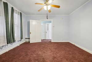 Unfurnished bedroom with carpet floors, radiator heating unit, crown molding, and a ceiling fan