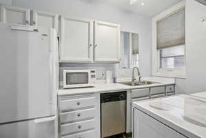 Kitchen featuring white cabinetry, white appliances, and light countertops