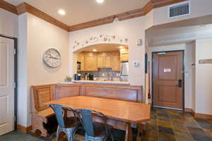 Dining space featuring ornamental molding, recessed lighting, dark stone finish floors, and arched walkways