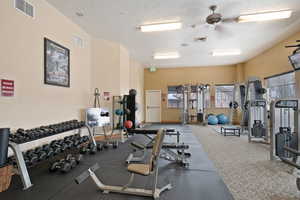 Exercise room featuring a textured ceiling and a ceiling fan