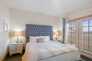 Bedroom featuring dark colored carpet and baseboards