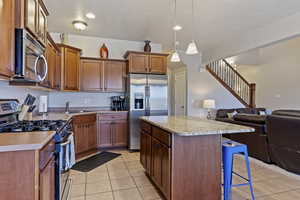 Kitchen with stainless steel appliances, open floor plan, a center island, a breakfast bar, and light tile patterned floors