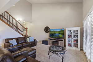Carpeted living room featuring a high ceiling and a glass covered fireplace