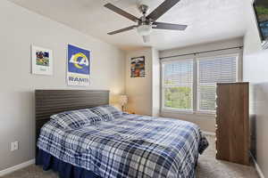 Bedroom with carpet floors, ceiling fan, and a textured ceiling