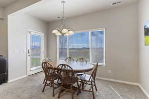 Carpeted dining area with baseboards and hanging lights