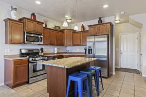 Kitchen featuring stainless steel appliances, a breakfast bar area, wood finish cabinets, and a kitchen island