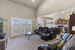 Living room featuring light colored carpet, recessed lighting, and a high ceiling