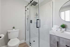 Bathroom with vanity, a marble finish shower, and light wood-type flooring
