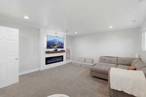 Carpeted living room featuring a glass covered fireplace and recessed lighting